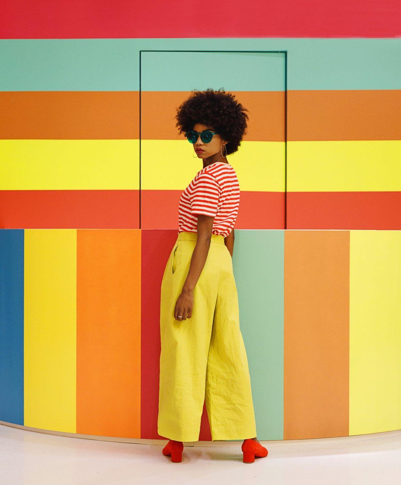 a woman standing in front of a colorful wall
