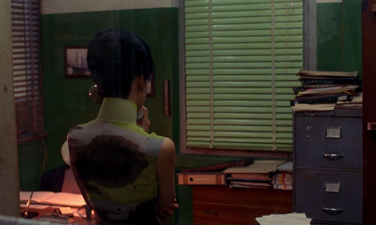 a woman standing in an office talking on a cell phone