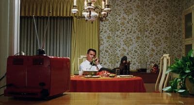 a man sitting at a table talking on a cell phone