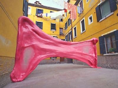 a pink sculpture is in front of a yellow building