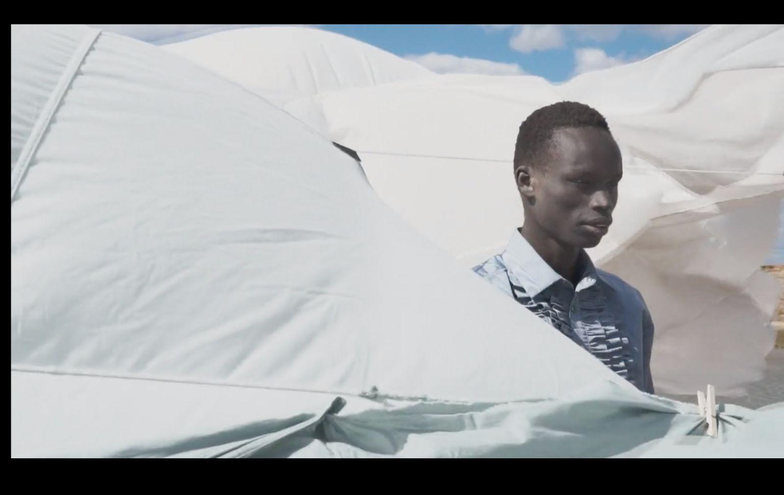 a young man standing in front of a white tent