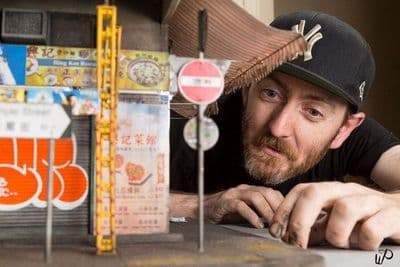 a man leaning on a table next to a model of a building