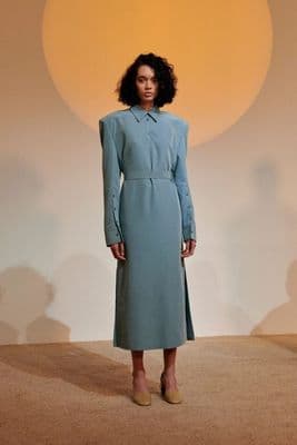 a woman in a blue dress standing in front of a wall