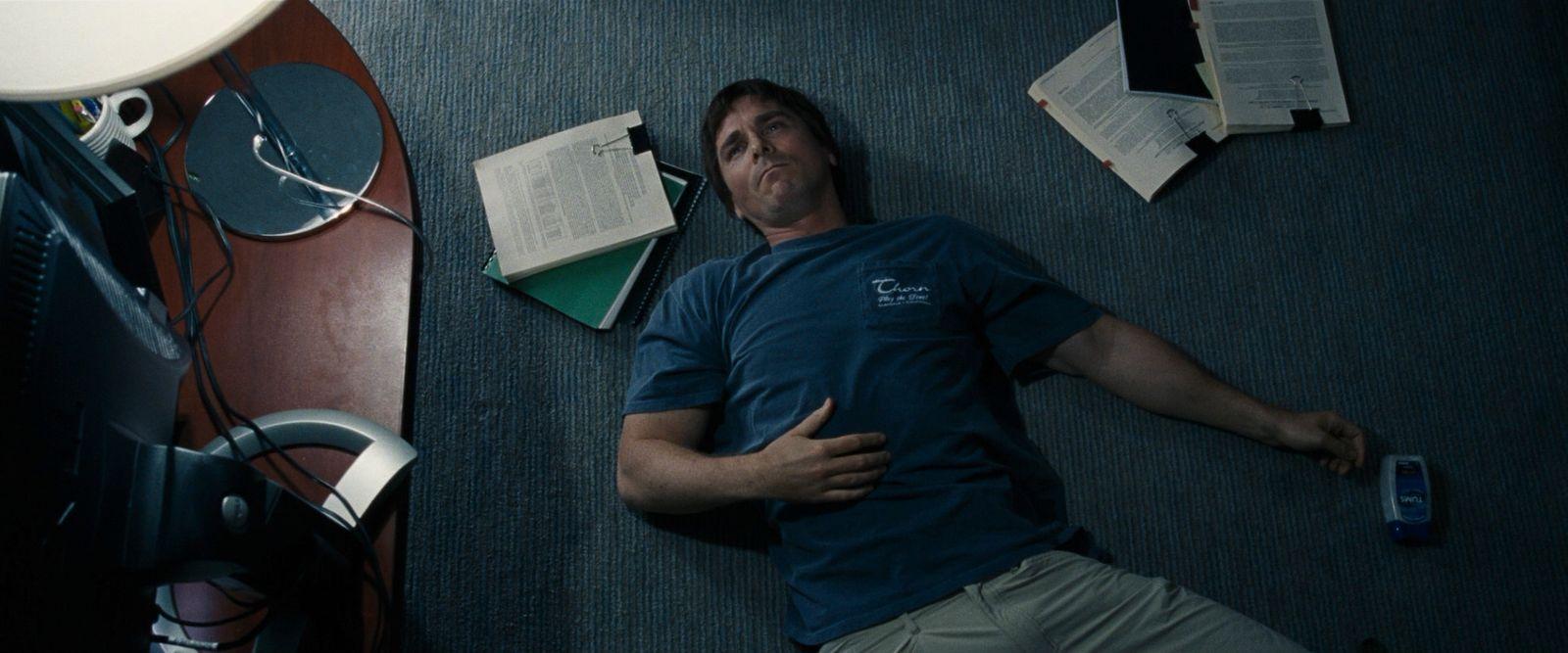 a man laying on the floor next to a computer monitor