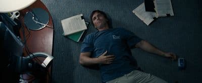 a man laying on the floor next to a computer monitor