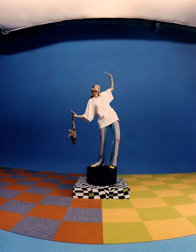 a woman standing on top of a black suitcase