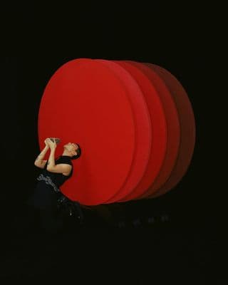 a woman standing in front of a large red object