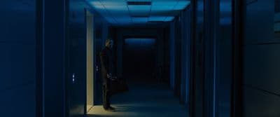 a man standing in a dark hallway with a briefcase