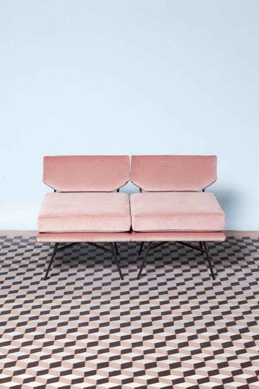 a pink couch sitting on top of a checkered floor