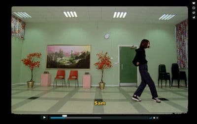 a woman walking through a room with a painting on the wall