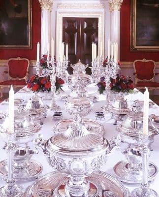 a dining room table is set with silver dishes and candles