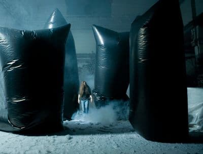 a woman standing between two large black bags