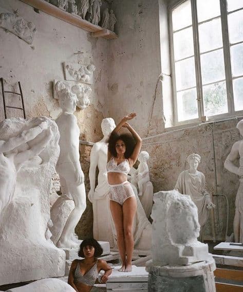 a woman in a white lingerie standing next to a statue