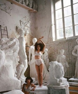 a woman in a white lingerie standing next to a statue