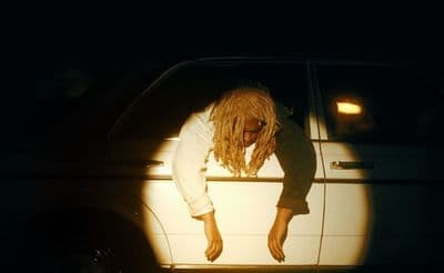 a man with dreadlocks leaning out of a car window