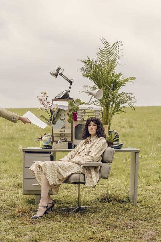 a woman sitting at a desk in a field