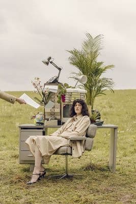 a woman sitting at a desk in a field