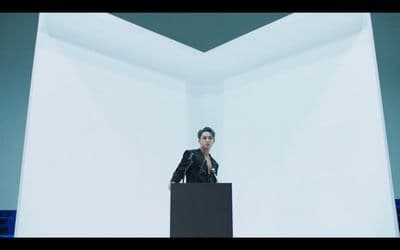 a man standing at a podium in front of a white wall