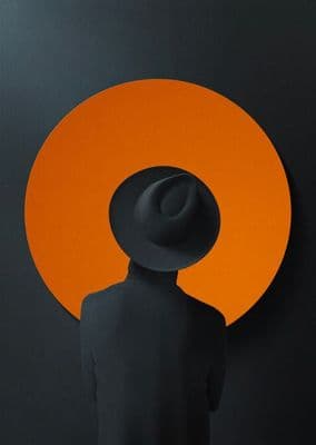 a person with a hat standing in front of an orange circle