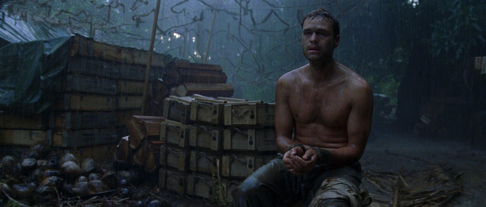 a shirtless man sitting on a pile of crates