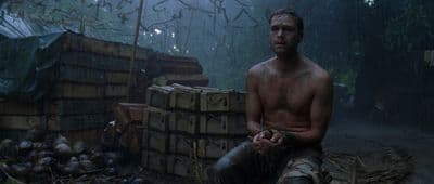 a shirtless man sitting on a pile of crates