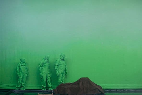 a room with three statues and a green wall