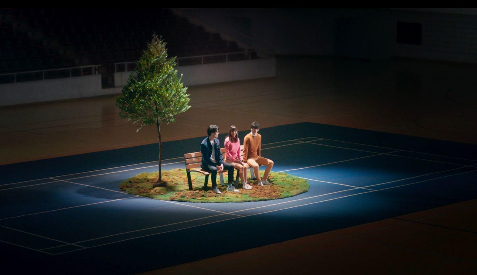 a group of people sitting on a bench next to a tree