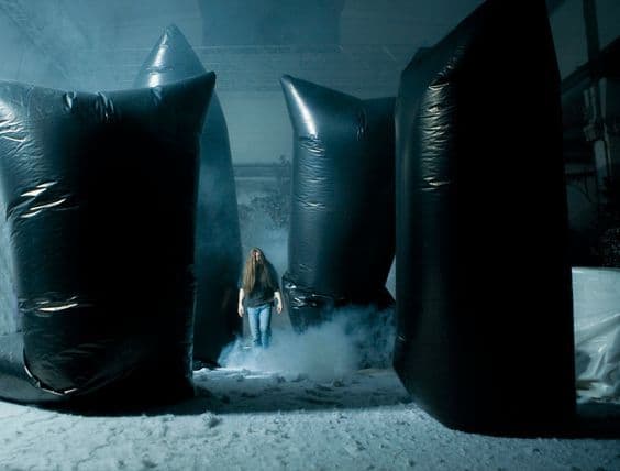 a woman standing between two large black bags