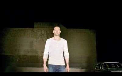 a man standing in front of a car in the dark