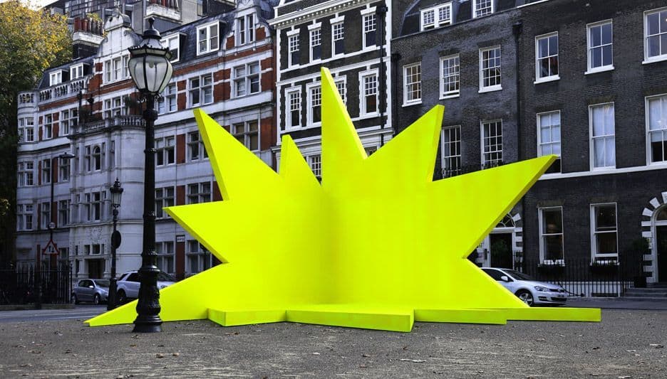 a large yellow piece of art sitting in the middle of a street