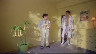 a couple of people standing in a room with a guitar