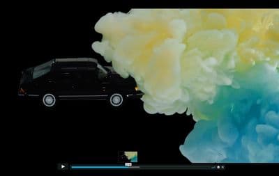 a black car driving through a colorful cloud of smoke