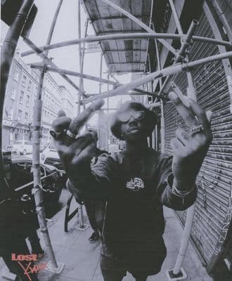a man holding up his hands while standing in front of a building