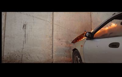 a white car parked next to a white wall