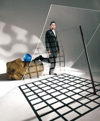 a man in a suit standing in front of a large rock