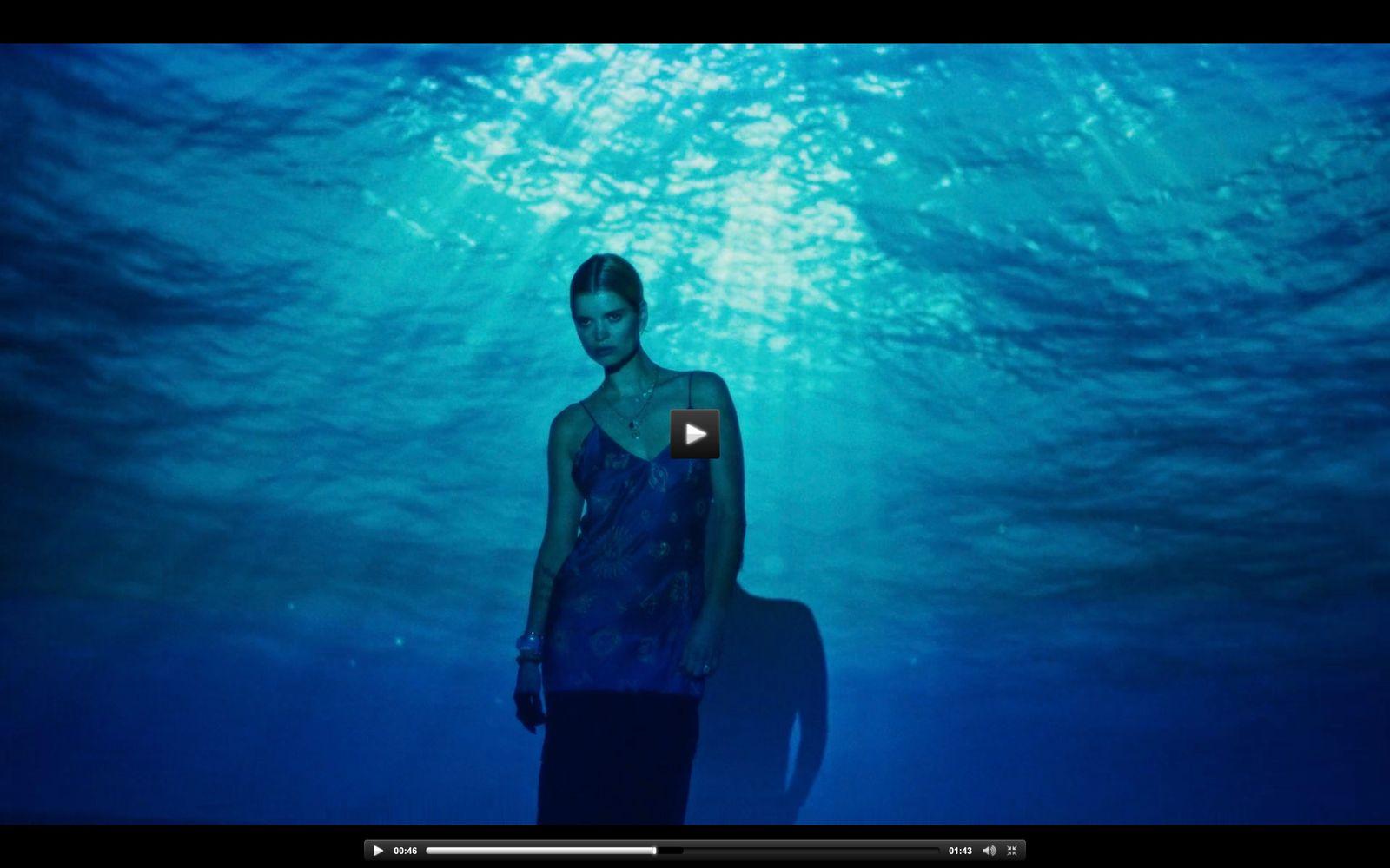 a woman in a blue dress standing under water