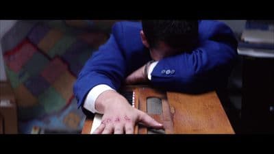 a man in a blue suit leaning over a wooden table