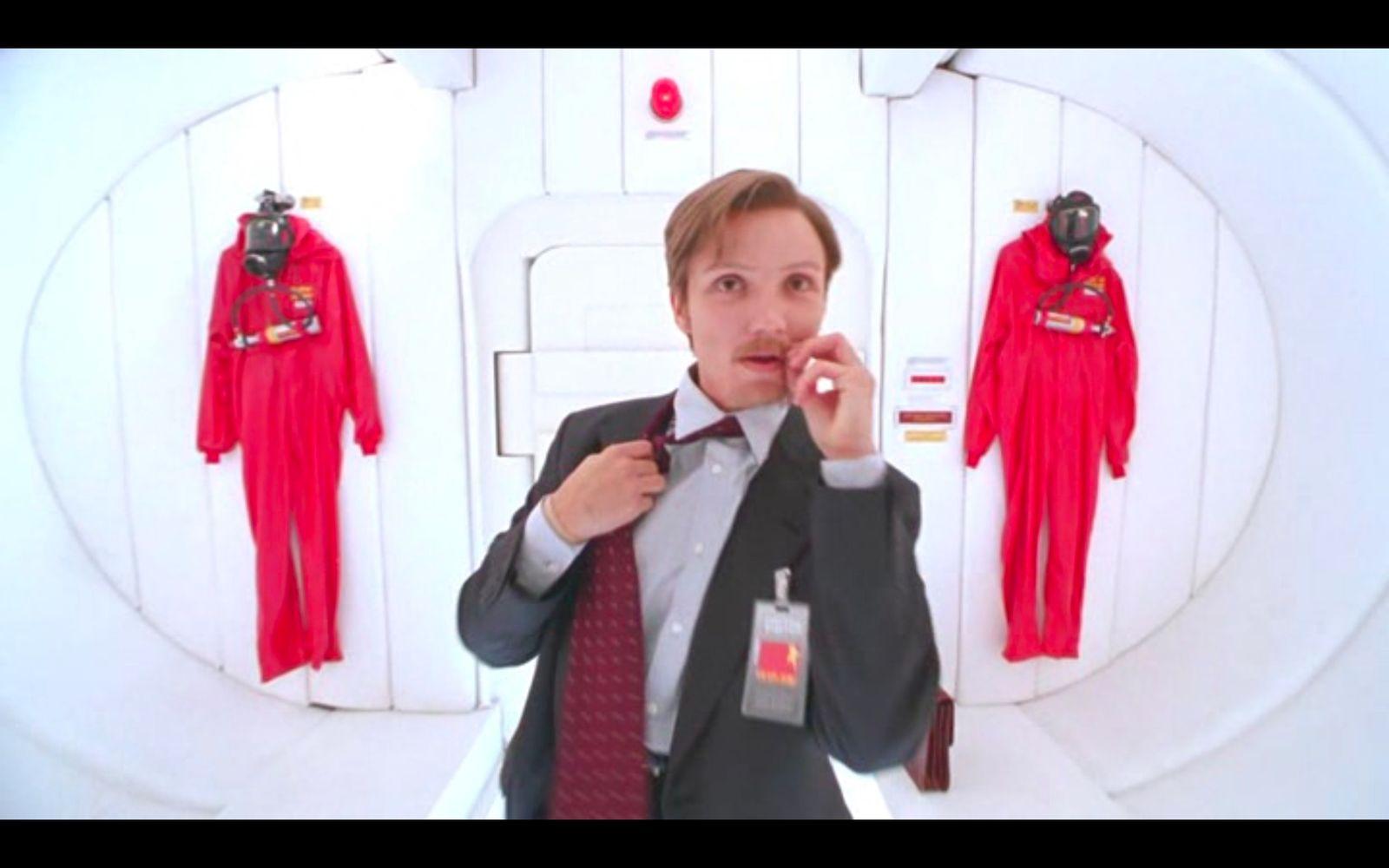 a man in a suit and tie standing in front of a display of manne