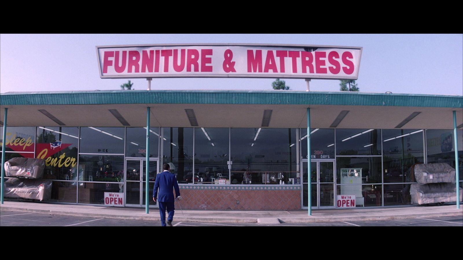 a man standing in front of a furniture and mattress store