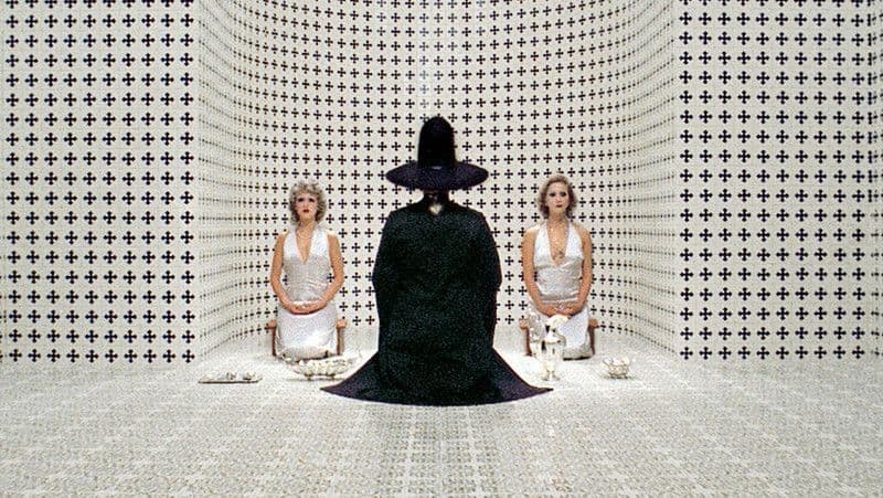two women sitting on chairs in front of a black and white wall