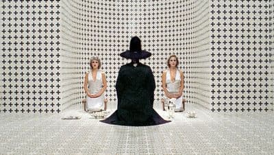 two women sitting on chairs in front of a black and white wall