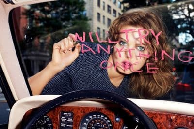 a woman sitting inside of a car holding a pink marker