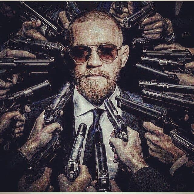 a man in a suit and tie surrounded by guns