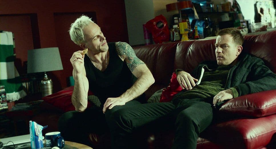 a couple of men sitting on top of a red couch