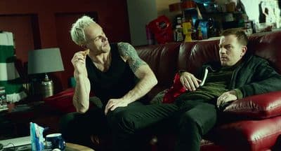 a couple of men sitting on top of a red couch