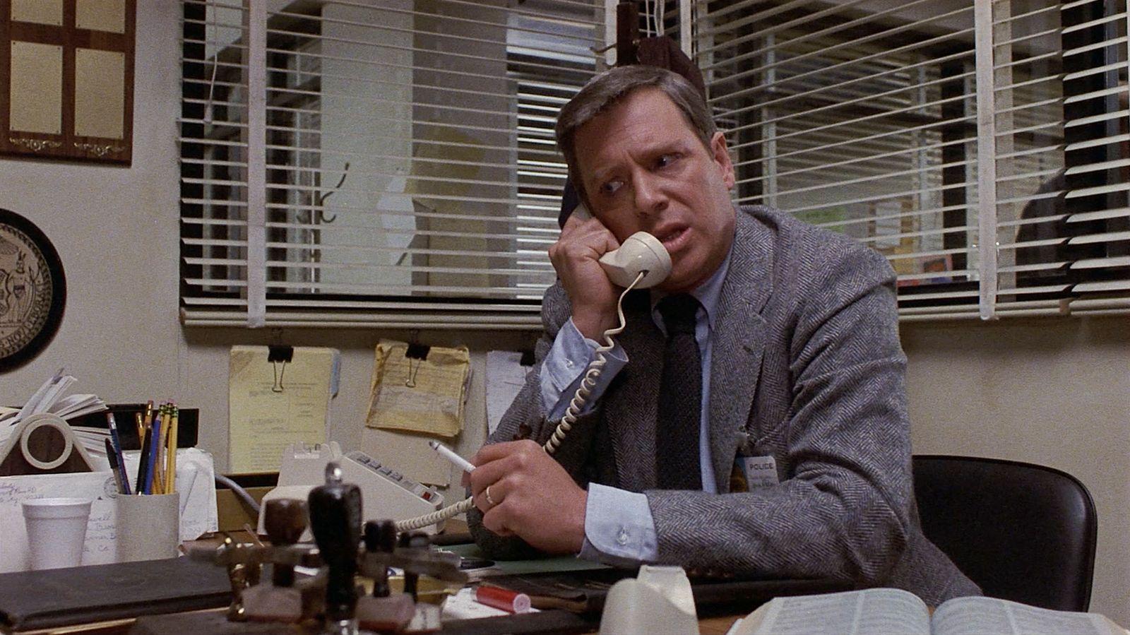 a man sitting at a desk talking on a phone
