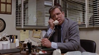 a man sitting at a desk talking on a phone