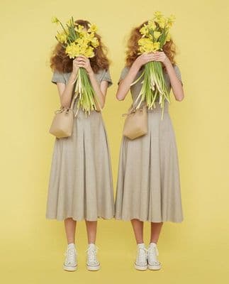 two women with flowers in their hair are standing in front of a yellow background