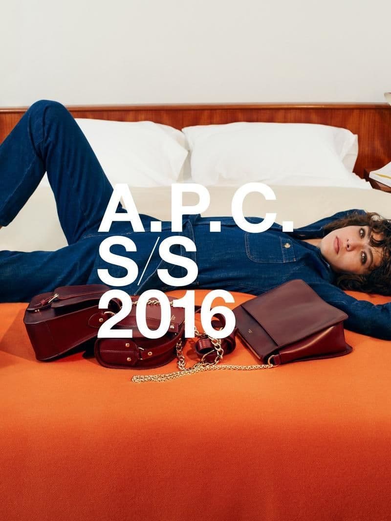a woman laying on top of a bed next to a purse