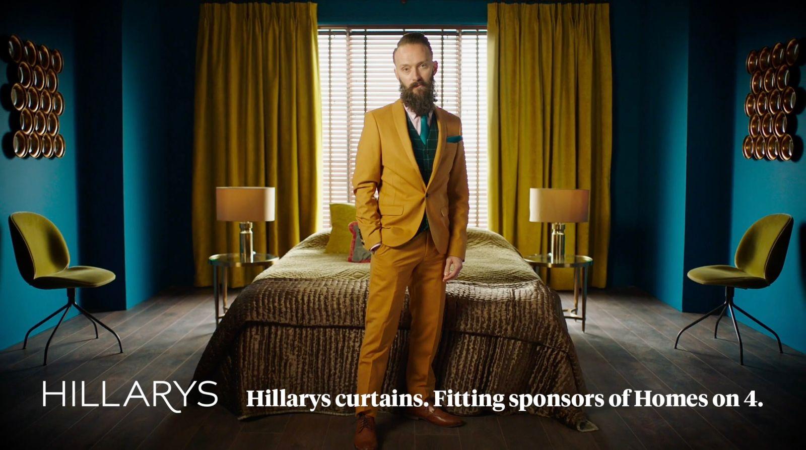 a man in a yellow suit standing in front of a bed